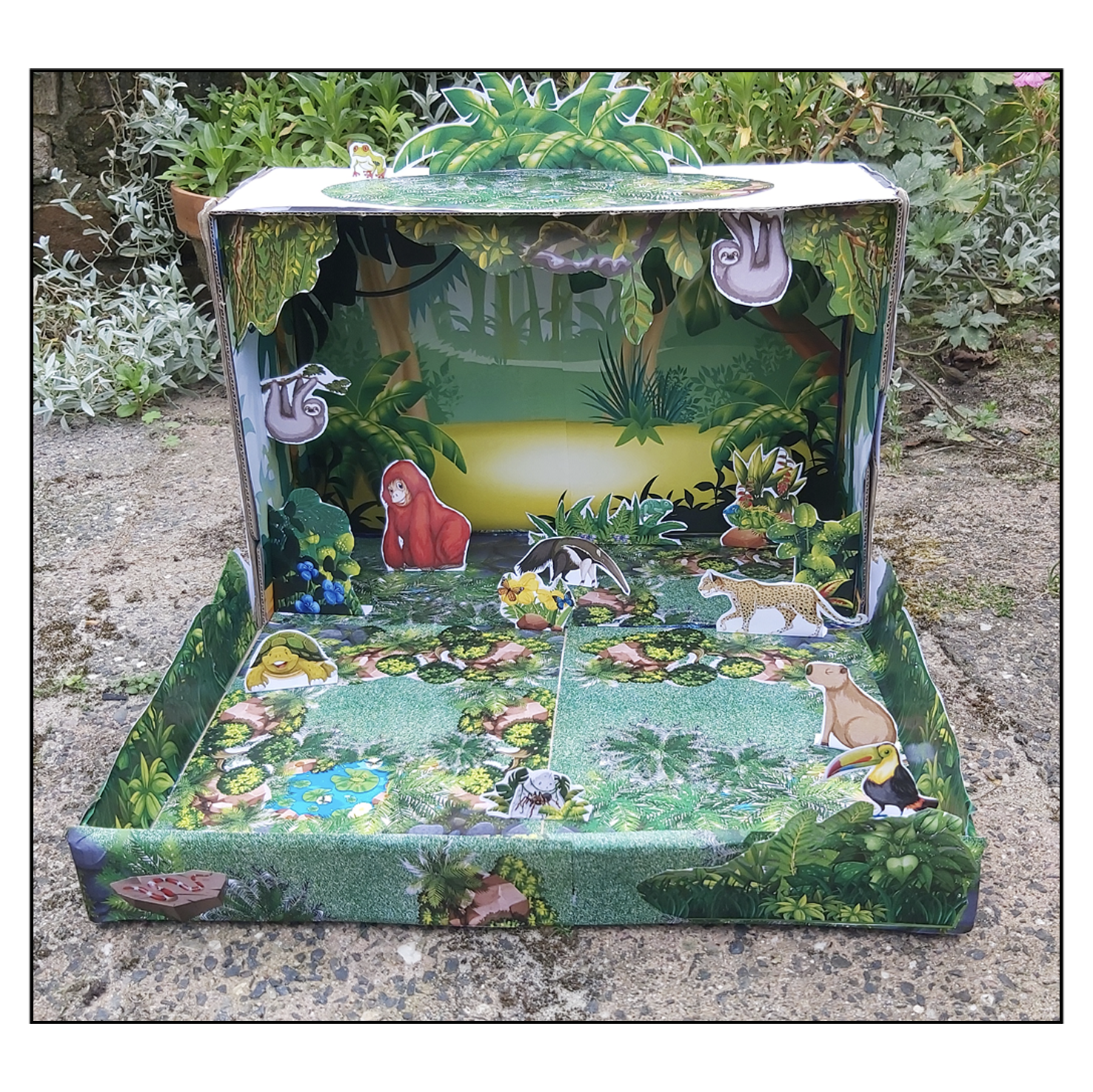 Completed printable Rainforest Habitat shoebox diorama for kids with tropical plants, jungle scenery and rainforest animals